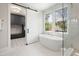Well-lit bathroom boasting a modern tub, glass-enclosed shower, and adjacent laundry room behind a sliding barn door at 4005 Brevard Pl, Raleigh, NC 27609