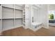 Custom closet design with wood floor, white cabinets, shelves, and a convenient bench with hooks for organized storage at 4005 Brevard Pl, Raleigh, NC 27609