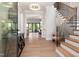 Bright foyer featuring wood floors, a staircase with black railings, and access to living areas at 4005 Brevard Pl, Raleigh, NC 27609