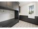 Well-lit laundry room featuring sleek cabinetry, modern countertops, a farmhouse sink, and stylish patterned flooring at 4005 Brevard Pl, Raleigh, NC 27609