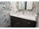 Close-up of a vanity in a powder room with a marble countertop and designer faucet with decorative wallpaper at 4005 Brevard Pl, Raleigh, NC 27609