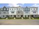 Row of townhouses featuring gray, white, and stone exteriors, and manicured landscaping at 701 Lucky Clover Way, Fuquay Varina, NC 27526