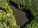 Aerial view showing home nestled in lush greenery beside a serene lake at 10305 Old Creedmoor Rd, Raleigh, NC 27613