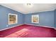 Bedroom with two windows, baseboard trim and red carpet at 1109 Mays Chapel Rd, Bear Creek, NC 27207