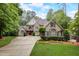 Elegant stone home featuring lush landscaping, a long driveway, and a welcoming red front door at 1300 Caistor Ln, Raleigh, NC 27614