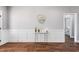Hallway with elegant wainscoting leads to bathroom; showcasing neutral wall color and wooden flooring at 137 Glenwood Pl, Kenly, NC 27542