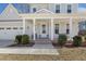 Inviting front porch with seating, white columns, and a well-manicured landscape at 221 Old Hickory Dr, Raleigh, NC 27603