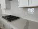 Close-up of kitchen with stainless steel gas range, quartz countertop and white herringbone backsplash at 3275 Roundly Rd # 10, New Hill, NC 27562