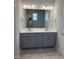 Bright bathroom featuring a gray double vanity, white countertop, framed mirror, and modern lighting fixtures at 65 Watermelon Dr, Franklinton, NC 27525