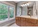 Double vanity bathroom with wood cabinets and large window at 6729 Greywalls Ln, Raleigh, NC 27614