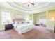 A spacious main bedroom features a tray ceiling, neutral paint, and a cozy sitting area with natural light at 7945 Parker Mill Trail, Fuquay Varina, NC 27526