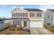 Two-story house with tan siding, white garage door, and landscaping at 105 Kcf Dr, Elon, NC 27244