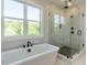 Modern bathroom featuring a soaking tub under a window and glass enclosed shower with matte black fixtures at 109 Evander Way, Pittsboro, NC 27312
