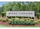 Ryan's Crossing stone community sign surrounded by verdant landscaping and colorful blooms at 109 Evander Way, Pittsboro, NC 27312