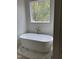 Elegant bathroom features a freestanding soaking tub beneath a large window at 129 Windel Dr, Raleigh, NC 27609