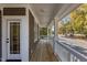 Long wooden porch with white railings and access door, overlooking a tree-lined street at 1300 Broad St # C, Durham, NC 27705
