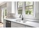 Bright kitchen features a farmhouse sink, white cabinets and a view to backyard at 2112 Stanchion St, Haw River, NC 27258