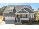 Gray house with white accents and a brick base, featuring a two-car garage and a front porch at 312 Trinity Creek Dr, Holly Springs, NC 27540