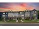 A row of new townhomes in various colors with manicured lawns and vibrant sunset backdrop at 433 Rowe Way, Knightdale, NC 27545