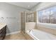 Well-lit bathroom featuring a glass-enclosed shower and a soaking tub next to a window at 7416 Capulin Crest Dr, Apex, NC 27539