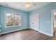 A bright bedroom with hardwood floors, a ceiling fan, and a large window at 7416 Capulin Crest Dr, Apex, NC 27539