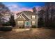 Charming two-story home with a stone facade, inviting entry, and professionally landscaped front yard at dusk at 7416 Capulin Crest Dr, Apex, NC 27539
