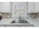 Bright kitchen sink features modern faucet, mosaic backsplash and window with white shutters at 1014 Holden Rd, Youngsville, NC 27596