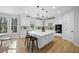 Modern kitchen boasts white cabinets, hardwood floors, a large island, and stainless steel appliances at 109 Aspenridge Dr, Holly Springs, NC 27540