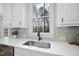 Kitchen features white cabinets, a farmhouse sink, and herringbone backsplash at 109 Aspenridge Dr, Holly Springs, NC 27540