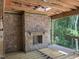 Spacious room with a stone fireplace, unfinished wood floors, and a wall of windows overlooking a wooded landscape at 274 Westhampton Dr, Pittsboro, NC 27312