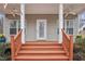 Inviting front porch with white columns, a welcoming door, and painted wood railings at 4716 Howe St, Durham, NC 27705