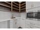 Pantry featuring white cabinets, wood shelves, stone backsplash, and gold accents at 4912 Hidden Pasture Way, Zebulon, NC 27597