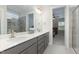 Double vanity bathroom with gray cabinets, a walk-in shower, and view into bedroom at 1141 Logperch Way, Wendell, NC 27591