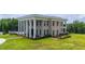 A side view showcasing a two-story home with grand columns and lush green grounds at 14425 Nc-96 N Hwy, Zebulon, NC 27597