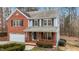 Two-story brick home with a wrap-around porch and wooded backyard at 6645 Austin Creek Dr, Wake Forest, NC 27587