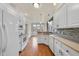 Bright kitchen showcasing white cabinets, wood floors, and stainless steel appliances at 701 Occoneechee Dr, Fuquay Varina, NC 27526