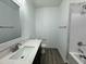 Modern bathroom features wood floors, a white vanity and countertop, a framed mirror, and a tub with marble-look tile surround at 100 Preacher Ln, Angier, NC 27501