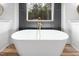 White freestanding bathtub with gold faucet and dark gray accent wall at 1040 Southern High School Rd, Burlington, NC 27215