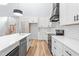 Well-lit kitchen boasts white cabinets, stainless steel appliances, an island with a sink, and wood flooring at 1040 Southern High School Rd, Burlington, NC 27215