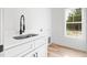 Bright laundry room features a stainless steel sink, white cabinetry, and a window letting in natural light at 1040 Southern High School Rd, Burlington, NC 27215