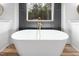 Elegant freestanding tub with gold fixtures in a modern bathroom with a view of the trees at 1040 Southern High School Rd, Burlington, NC 27215