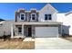 Two-story home with a gray and white exterior, stone accents, attached two-car garage, and well-manicured lawn at 156 Babbling Brook Dr, Clayton, NC 27520