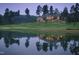 Stunning lakefront house with a manicured lawn and mature trees reflected on the water at twilight at 32602 Archdale, Chapel Hill, NC 27517