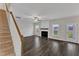 Open living room featuring dark wood floors, ceiling fan, fireplace and stairway at 8 Looping Horse Cir, Angier, NC 27501