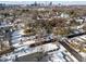 Aerial view of a neighborhood with houses, snow-covered yards, mature trees, and a city skyline in the distance at 819 Cumberland St, Raleigh, NC 27610