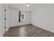 Simple bedroom with wood-look flooring, white walls, and a small window with blinds at 819 Cumberland St, Raleigh, NC 27610