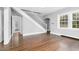 Spacious room featuring hardwood floors, a white staircase, and large windows for natural light at 945 Sycamore St, Rocky Mount, NC 27801