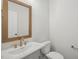 Half bathroom featuring bronze fixtures, white sink, toilet and vanity at 4717 Cypress Tree Ln, Raleigh, NC 27612