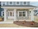 Inviting front porch with stone accents, white columns, and a charming front door at 514 Glenkirk Pl, Garner, NC 27529