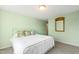 Light green bedroom with a white metal bed frame, floral pillows, and a large mirror at 5765 G Snow Camp Rd, Graham, NC 27253